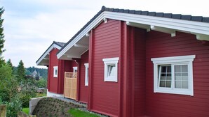 Una casa roja con puerta blanca, un pequeño porche y una ventana.
