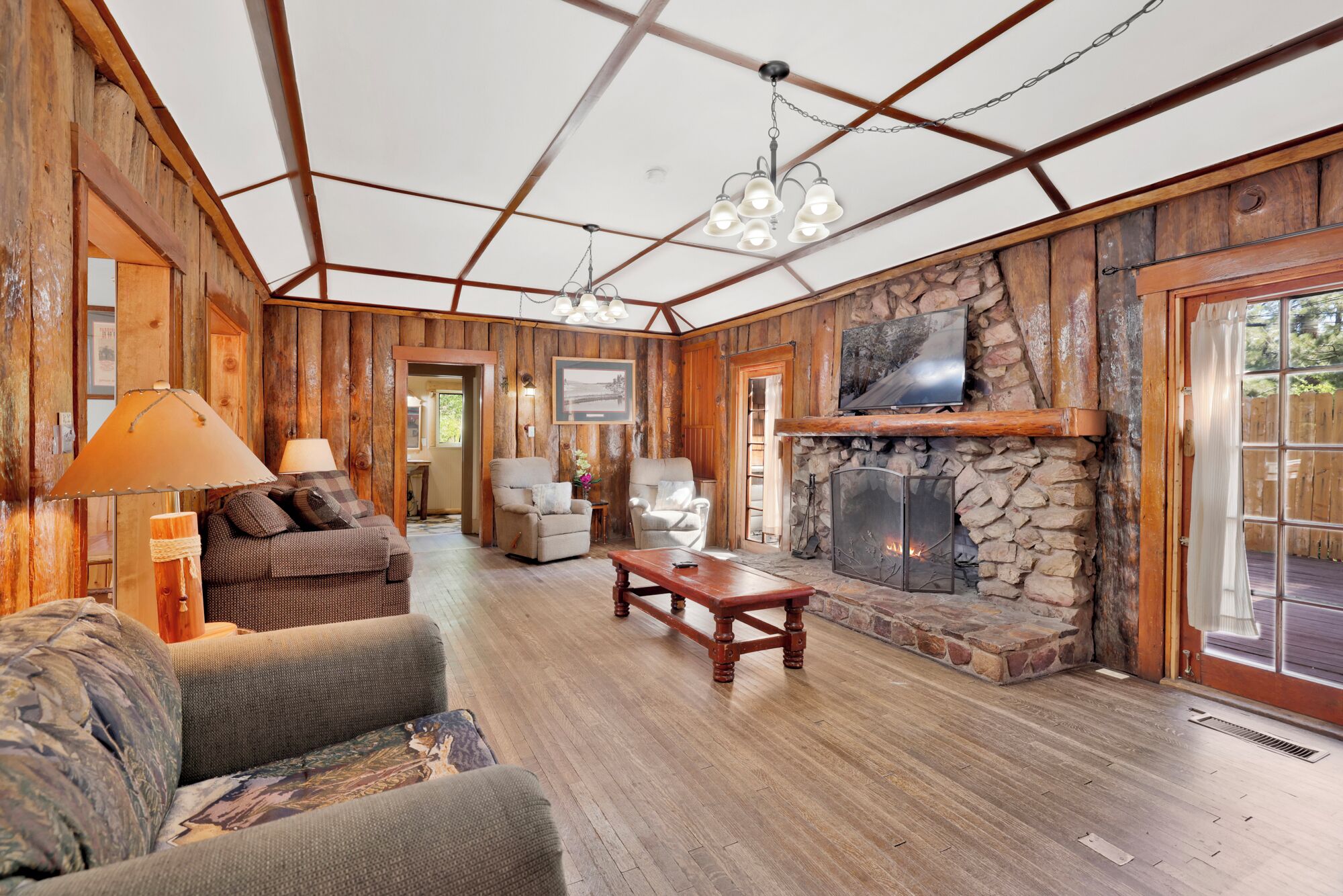 Un intérieur rustique avec une cheminée en pierre, des murs en bois et un coin salon confortable avec un canapé et des fauteuils.