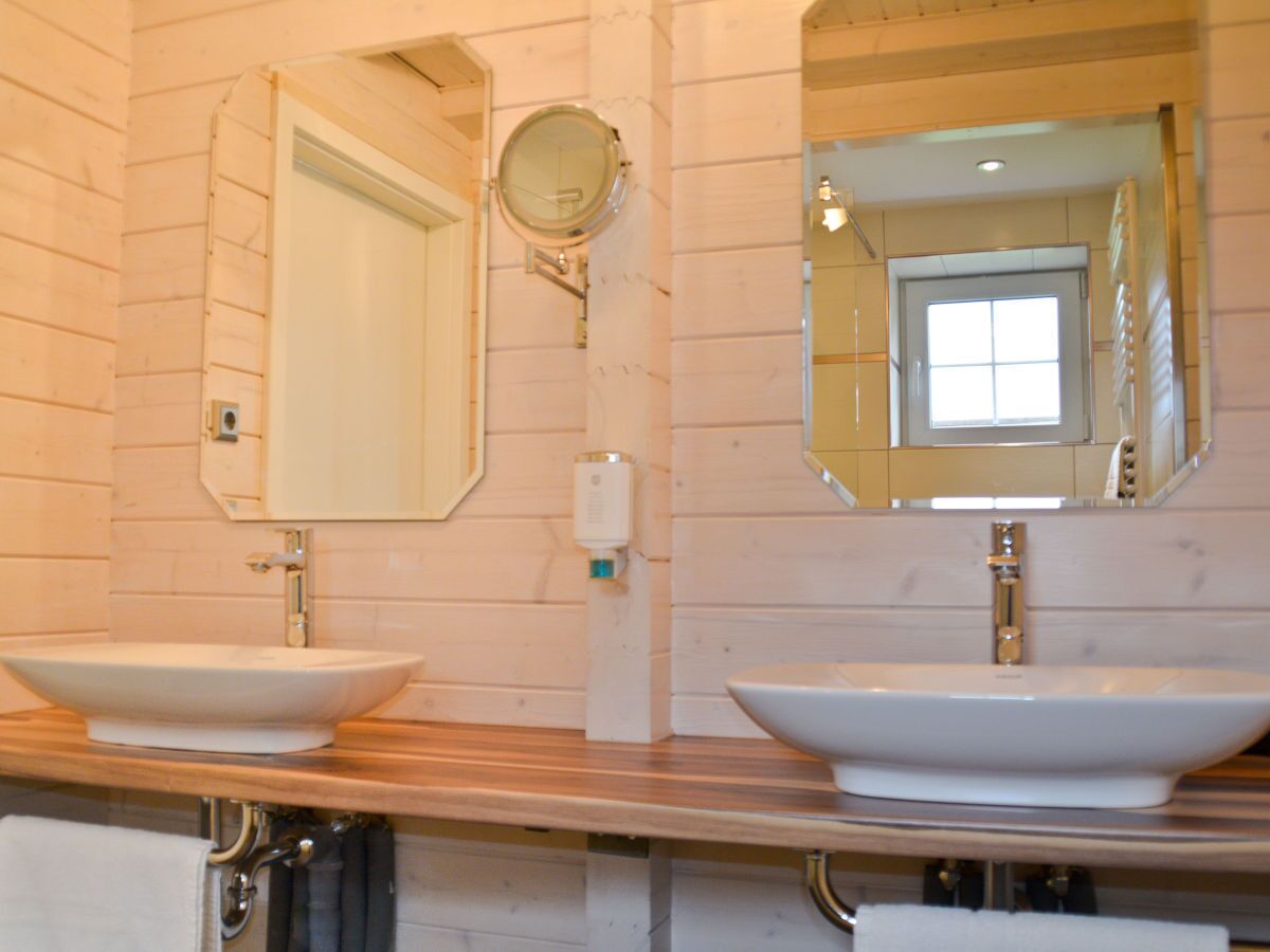 A bathroom with two large white sinks, a mirror above each sink, and a towel rack below the left sink.
