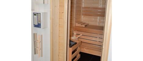 Uma sala de sauna com bancos de madeira e um painel de controle.