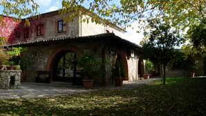 A courtyard with a stone building, a parked car, and potted plants. - La Caveja (Pietravairano)
