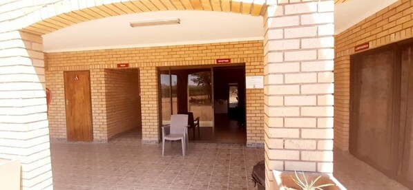 Zona de recepción con pared de ladrillo, mostrador y una silla.