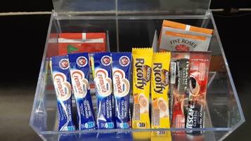 A clear plastic container with various coffee creamer packets and a few other items.