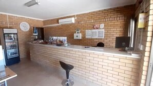 A restaurant with a brick wall, a refrigerator, a counter, and a stool.