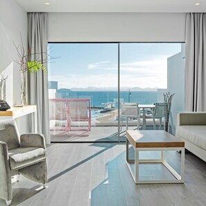Un salon moderne doté d’une grande porte-fenêtre coulissante donnant sur un balcon avec vue sur la piscine.