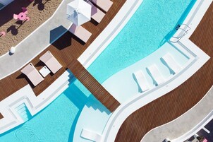 Una piscina al aire libre, sombrillas, sillones reclinables de piscina