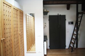 Ein Flur mit Holfachschränken, einer Tür mit schwarzem Rahmen und einer an der Wand lehnten Leiter.