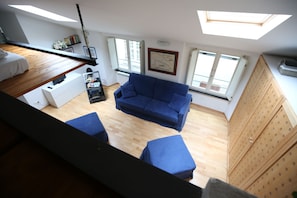 A room with a blue sofa, wooden flooring, a white desk, and a skylight. - Loft at the aquarium (with possibility of parking) (Genova)
