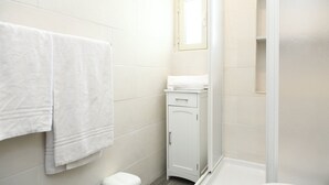 Une salle de bain comprenant des toilettes, un petit meuble de rangement et un espace douche.