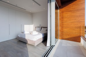 A modern bedroom with a bed, a wardrobe, and a wooden wall. - Napa Hills Seaview Villas (Ayia Napa)