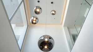 Ein modernes Interieur mit hoher Decke, kugelförmigen Pendelleuchten und einer Glaskonstruktion.