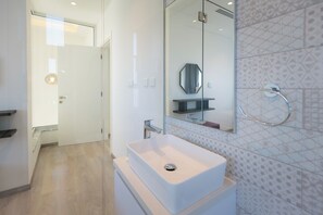 A modern bathroom with a white sink, a mirror, and a shower area. - Napa Hills Seaview Villas (Ayia Napa)