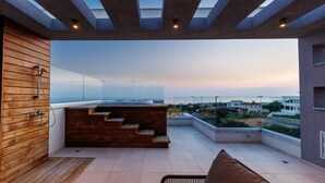 Eine Dachterrasse mit einer Holzbank, einem kleinen Tisch und Blick auf die Stadt.