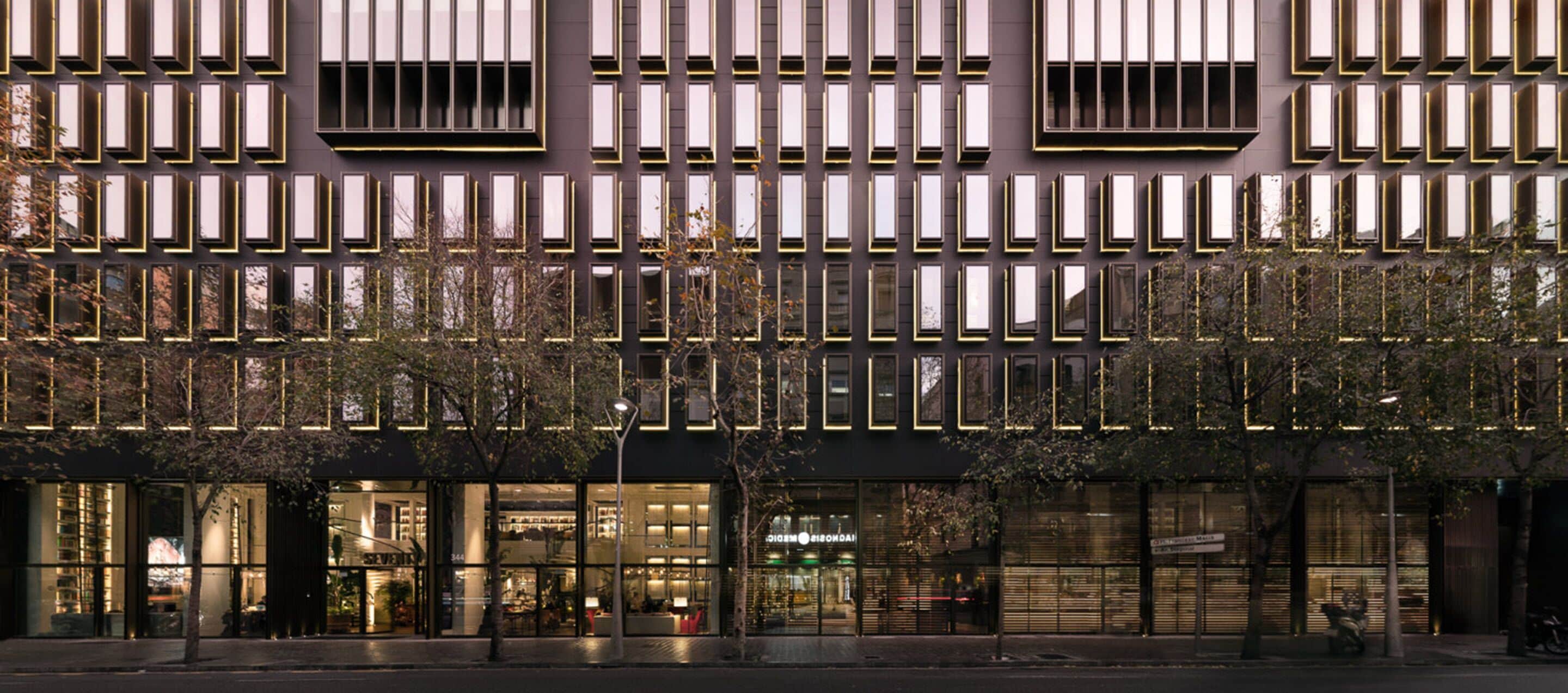 A modern building facade with a grid of windows and a series of balconies.