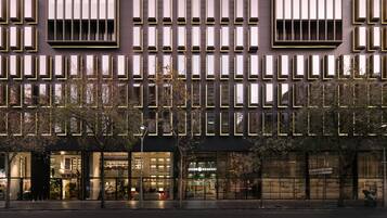 A modern building facade with a grid of windows and a series of balconies.