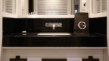 Un baño moderno con un lavabo negro, dos grifos y un perchero con dos toallas blancas.