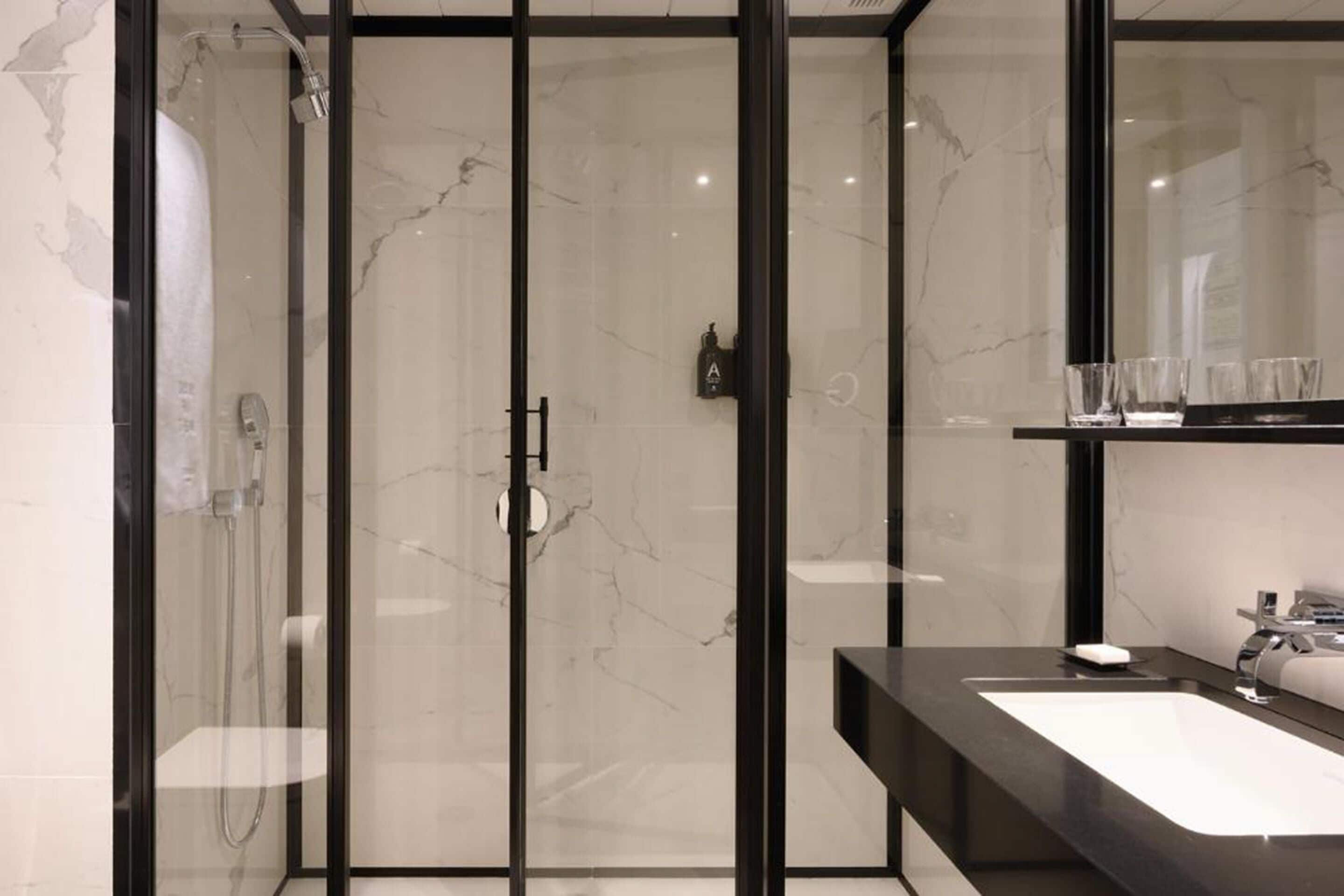 Une salle de bain moderne avec une douche à parois de verre, un plan de toilette noir et un grand miroir.