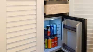 Un refrigerador compacto con compartimento congelador, que contiene bebidas y un microondas.