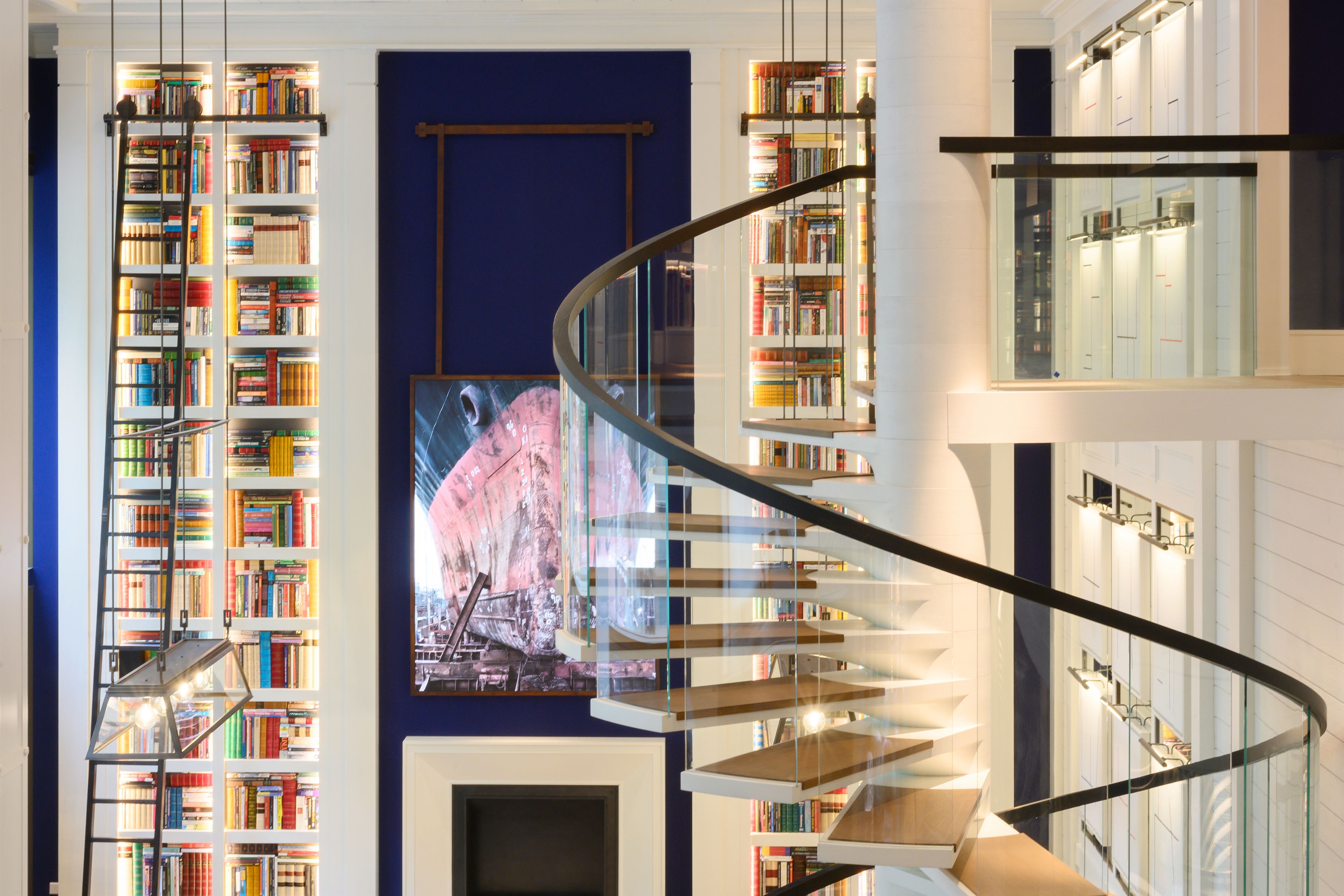 Una biblioteca moderna con una escalera de caracol, estanterías y un mural grande.