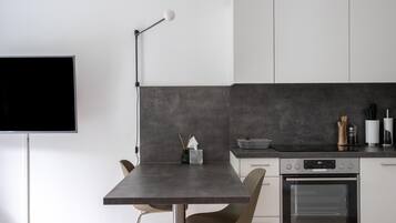 A modern kitchen with a dark countertop, a built-in oven, and a wall-mounted TV.