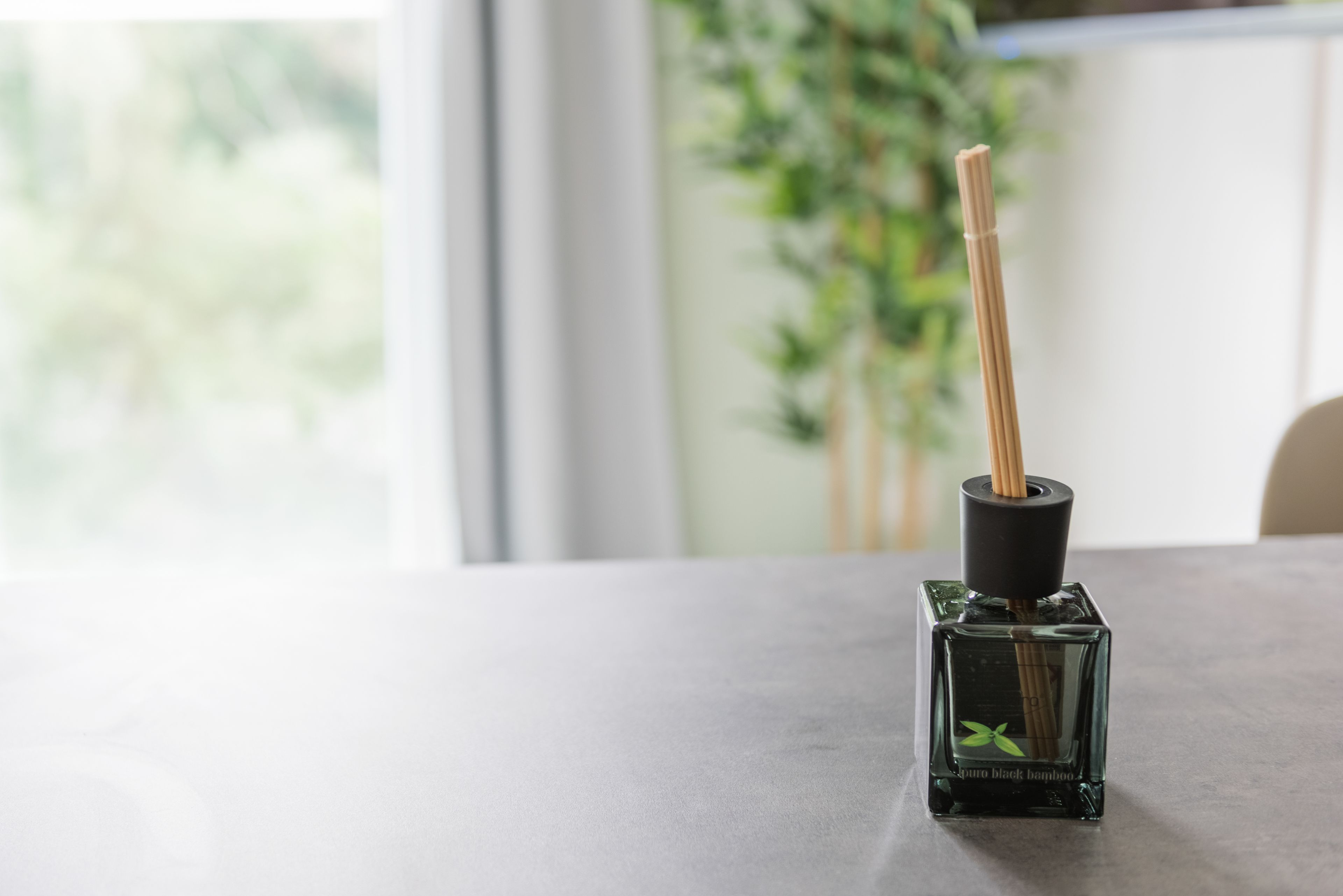 Una botella de vidrio con un palito de bambú sobre una mesa.