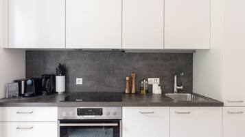 A modern kitchen with white cabinets, a stainless steel sink, and a built-in oven.