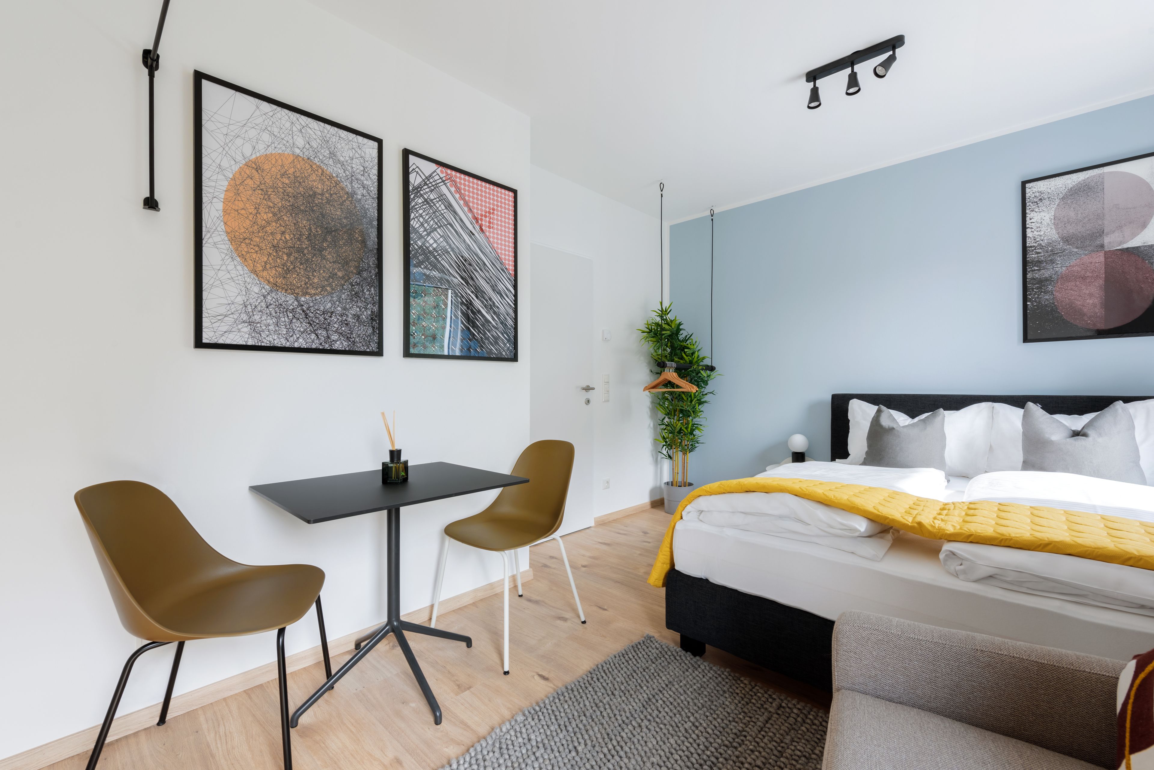 Una habitación de hotel moderna con una cama, un escritorio, dos sillas y obras de arte en las paredes.