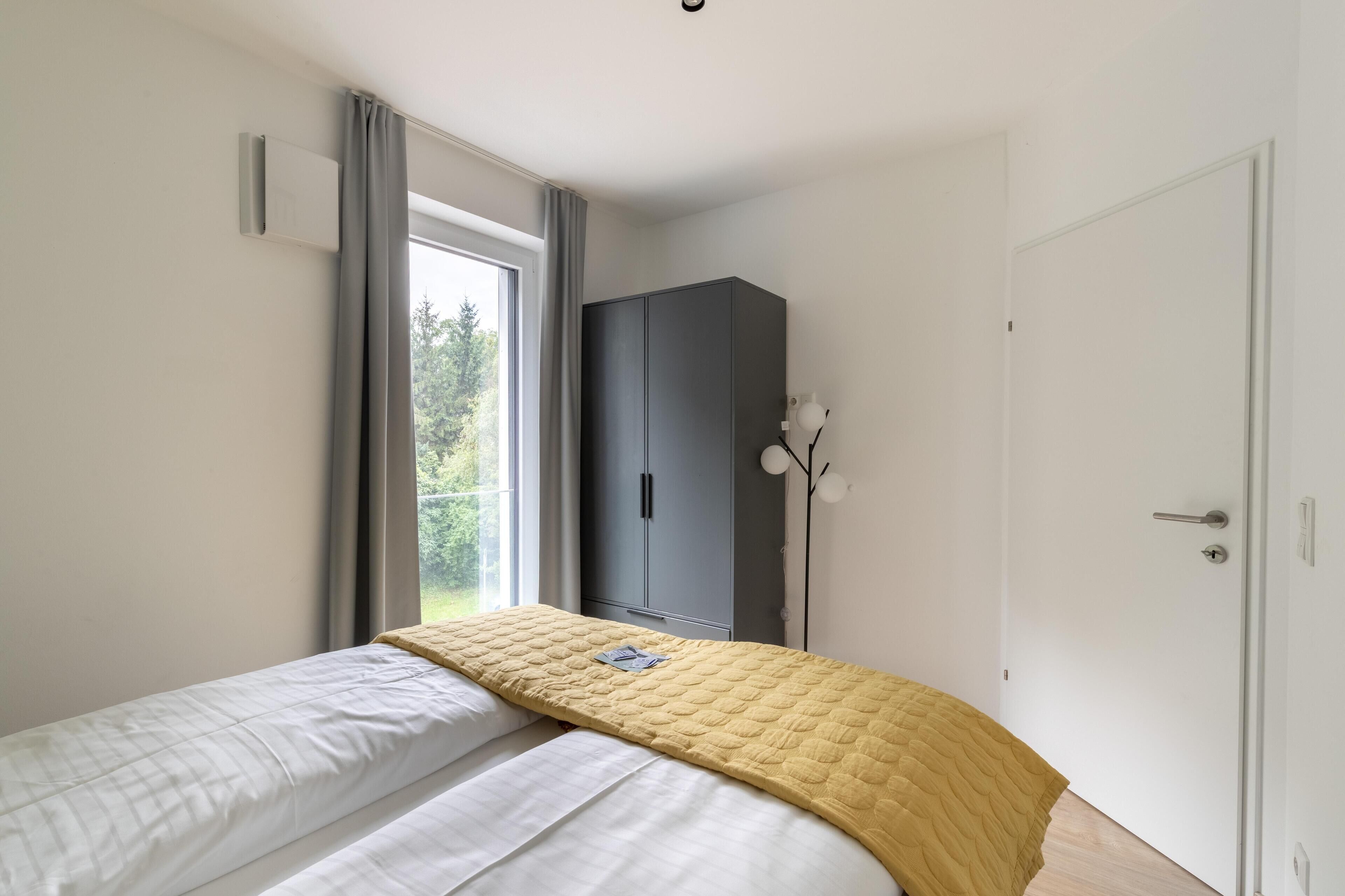 Un dormitorio con cama, armario, puerta y ventana.