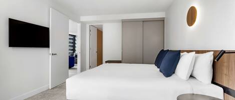Quarto de hotel moderno com uma cama grande, uma televisão de tela plana na parede e uma parede de destaque em madeira.