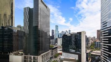 A cityscape with modern high-rise buildings, including a prominent glass skyscraper and a building with a unique geometric facade.