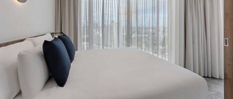 Un hotel moderno con una cama grande, vistas a la ciudad y una lámpara de pared redonda.
