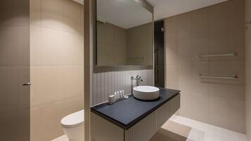 Un baño moderno con un inodoro blanco, un lavabo redondo y un espejo encima.