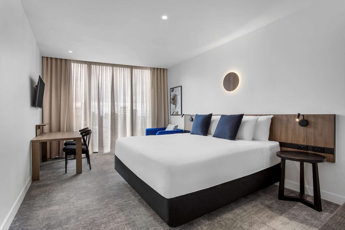 Une chambre d’hôtel moderne, dotée d’un grand lit, d’un bureau et d’une chaise.