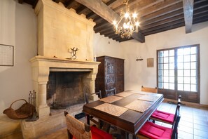 A room with a stone fireplace, wooden furniture, and a large window.