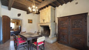 A dining area with a wooden table and chairs, a fireplace, and a large wooden cabinet with intricate carvings. - Homerez - House near Saintes-Maries-de-la-Mer (Saintes-Maries-de-la-Mer)