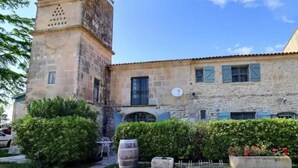 A stone building with a tower, a garden with a barrel, and a fence. - Homerez - House near Saintes-Maries-de-la-Mer (Saintes-Maries-de-la-Mer)