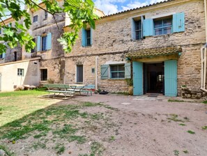 Un bâtiment en pierre avec une cour, un banc et une table.