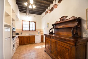 Une cuisine avec des meubles en bois, un lave-vaisselle, un four à micro-ondes et une fenêtre avec des rideaux.