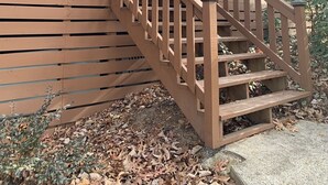 A wooden cabin with a porch and a staircase leading to the entrance.