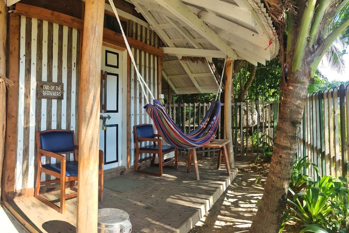 A wooden porch with striped walls, a hammock, and two chairs.