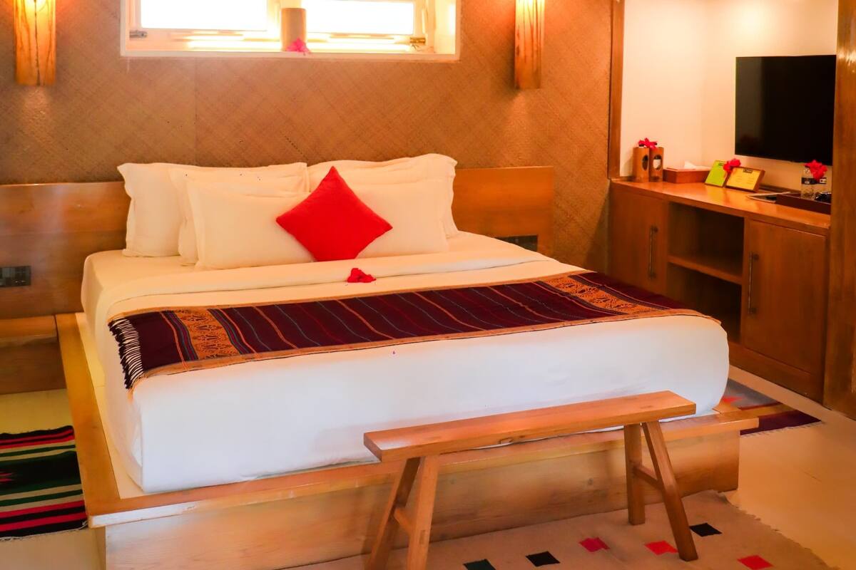 A hotel room with a bed, bedside table, and a mirror.