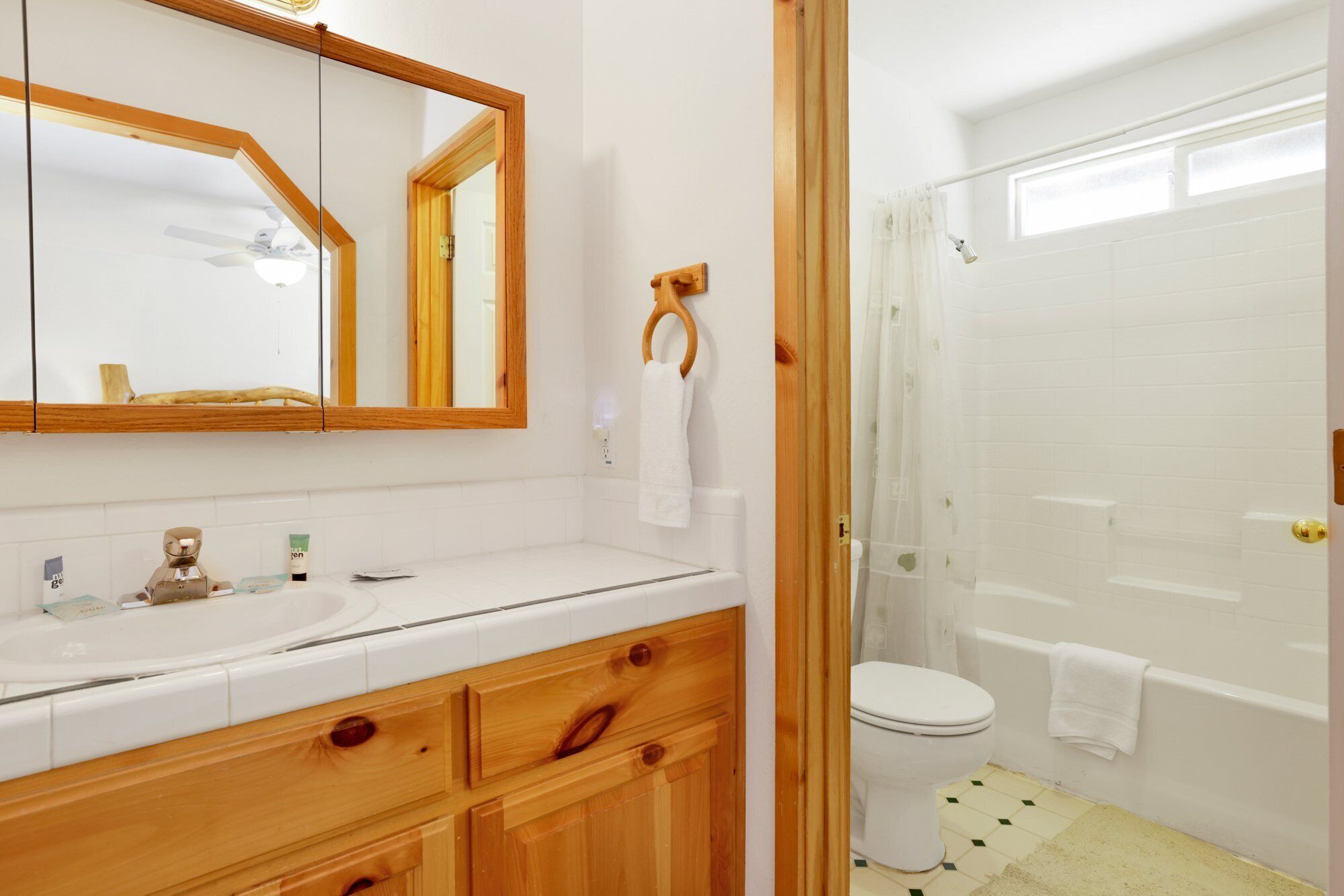 Une salle de bain avec un meuble-lavabo en bois, un grand miroir, des toilettes et un espace douche.