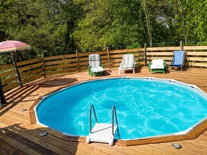 A swimming pool with a wooden deck, lounge chairs, and a wooden fence. - Homerez - Festive House in Callen (Callen)