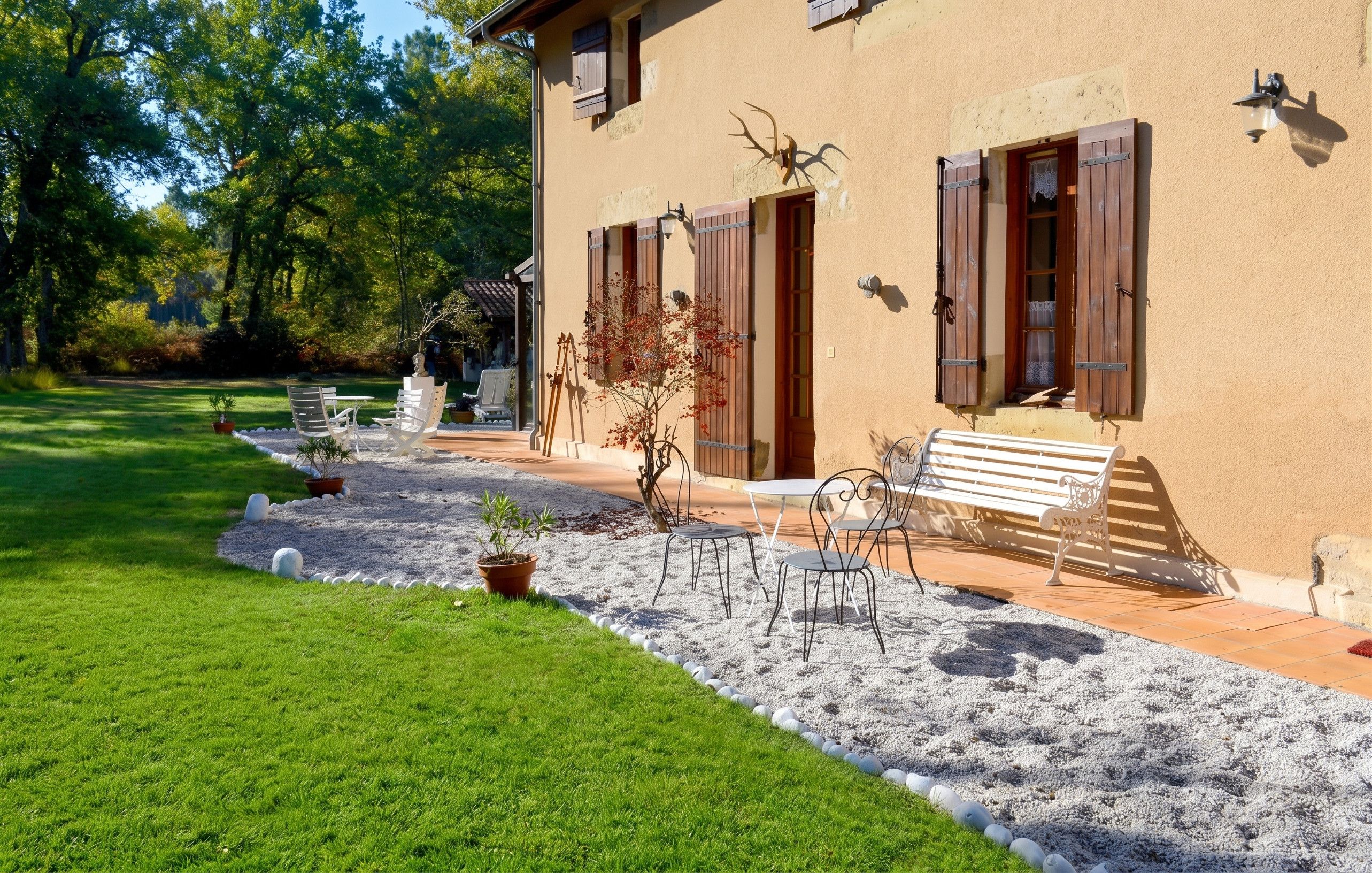 Una casa amb terrassa, mobiliari exterior i jardí.