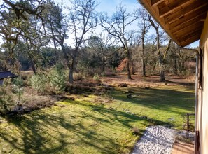 A wooden deck with a view of a grassy yard and trees. - Homerez - Festive House in Callen (Callen)