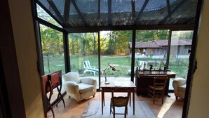 Una habitación con puerta de cristal que da a un patio con mesa, sillas y vistas al exterior.