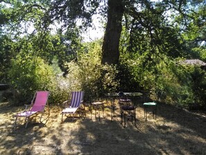 Un'area salotto all'aperto con tavolo e sedie, immersa nel verde e illuminata dalla luce naturale.