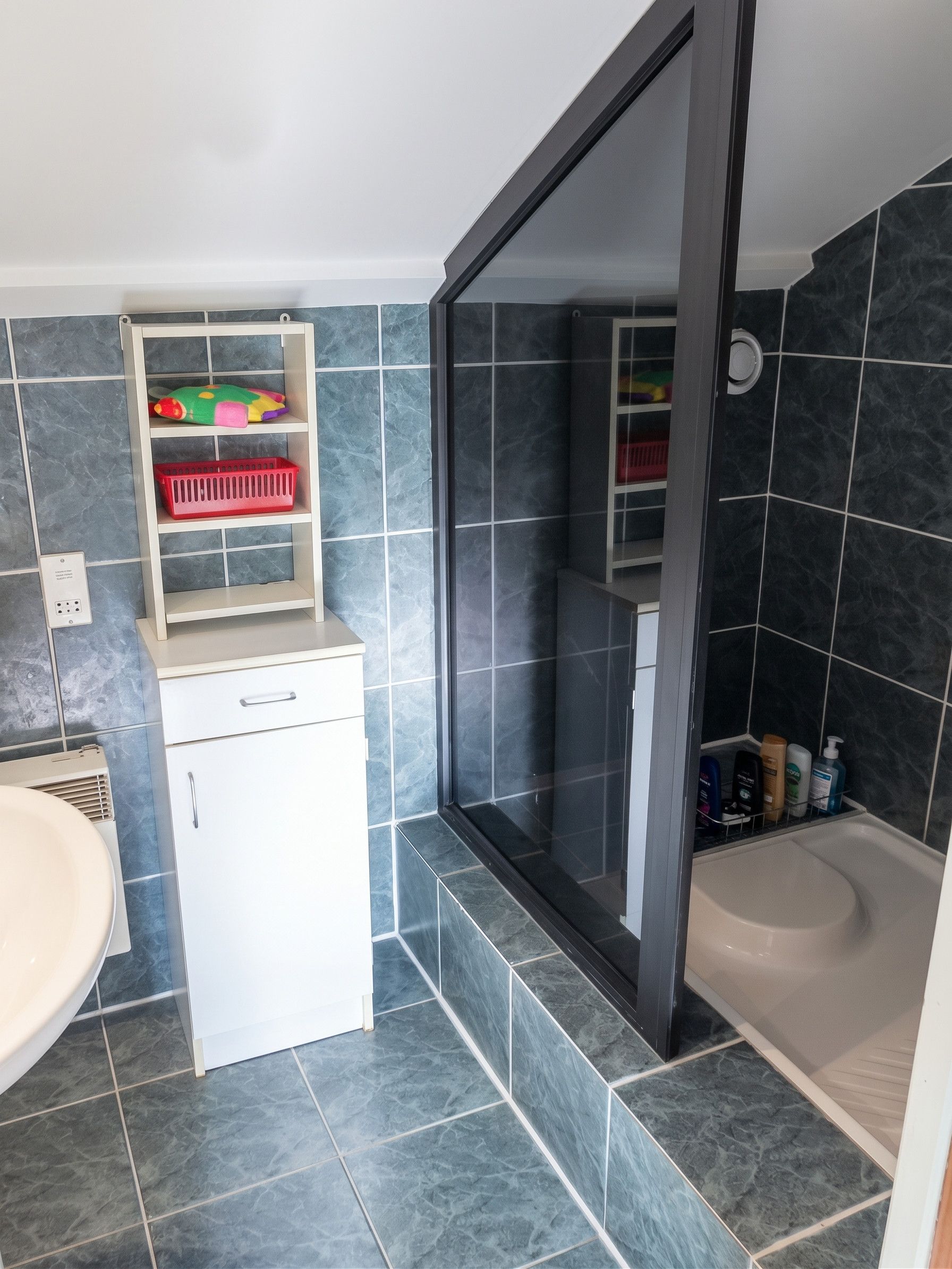 A modern bathroom with a white sink, a built-in toilet, and a shower area.