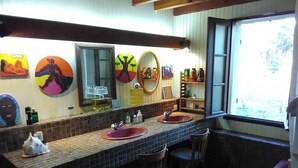 Un baño con piso de baldosas, un lavamanos, un espejo y una ventana.