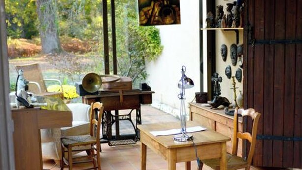 Un invernadero con una mesa de comedor, sillas, un sofá y vistas al exterior.